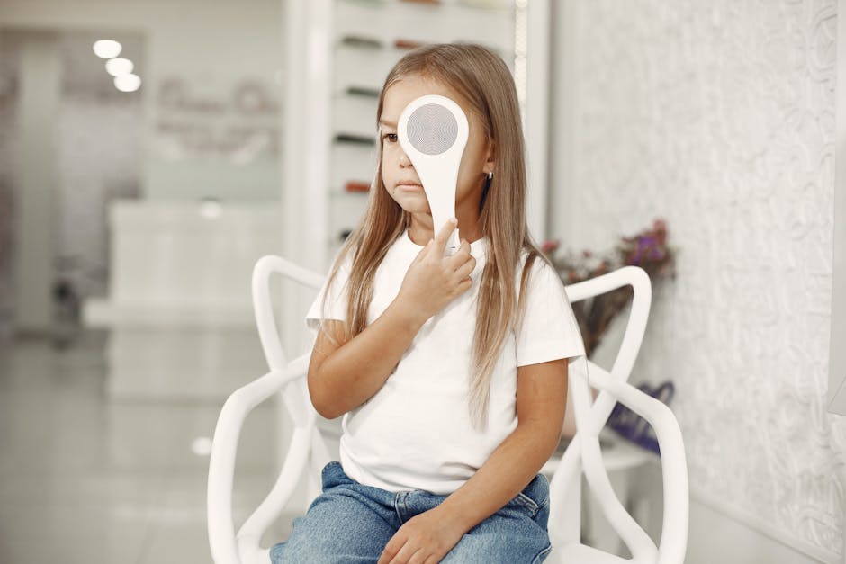 A young girl undergoing an eye test at an optician clinic, seated and holding an eye occluder.